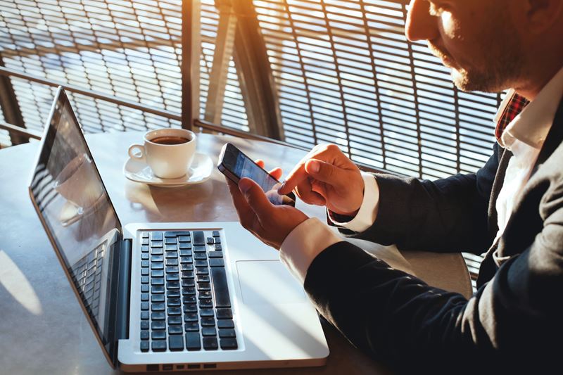 Business man on his laptop using his phone